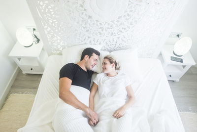 High angle view of couple lying on bed at home