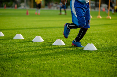 Low section of boy practicing slalom training drill on soccer field