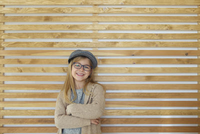 Portrait of smiling young woman standing against brick wall