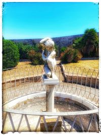 Statue by fountain against clear sky