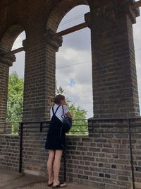 Full length of woman standing against brick wall