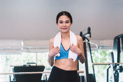 Portrait of woman with towel standing in gym