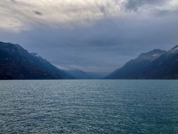 Scenic view of sea by mountains against sky