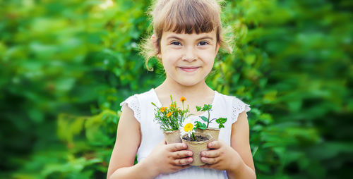 Portrait of smiling woman holding plant