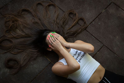 Lifestyle portrait of a beautiful woman with long hair resting on the ground holding her head