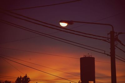 Low angle view of silhouette electricity pylon against sky during sunset