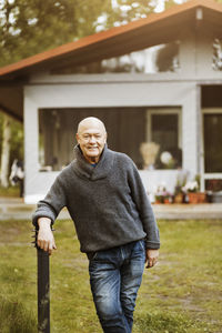 Portrait of happy senior gay man standing at yard