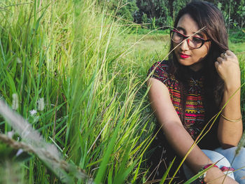 Beautiful young woman sitting amidst grass