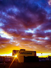 Road sign against dramatic sky during sunset