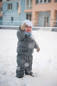 Full length of baby boy standing on snow covered land during winter