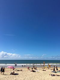 People on beach against blue sky