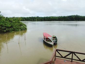 Boat moored on lake against sky