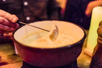 Close-up of manholding skewer on cheese fondue