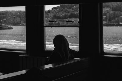 Rear view of woman looking through window