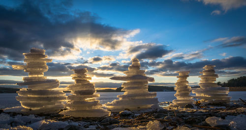 Stack of snow on land against sky during sunset