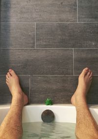 Low section of man in bathtub at bathroom