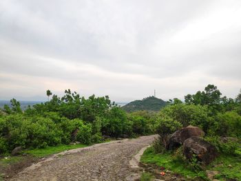 Dirt road leading towards temple against sky