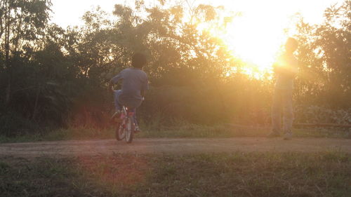 Man riding bicycle against sky during sunset