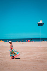 Woman on beach against blue sky