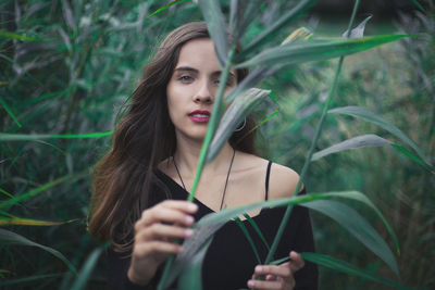 Portrait of young woman standing amidst plants