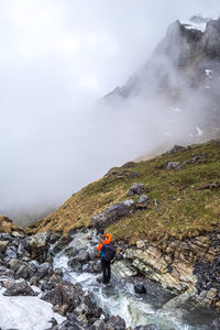 Man standing on rock against sky