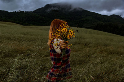 Woman holding flowers on grassy field