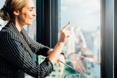Side view of woman looking through window