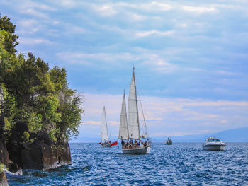 Sailboats sailing in sea against sky