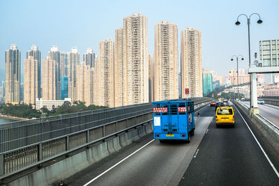 Vehicles on road amidst buildings against clear sky