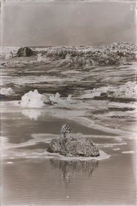 Scenic view of rocks on beach against sky