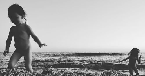 Full length of shirtless boy standing on beach against clear sky