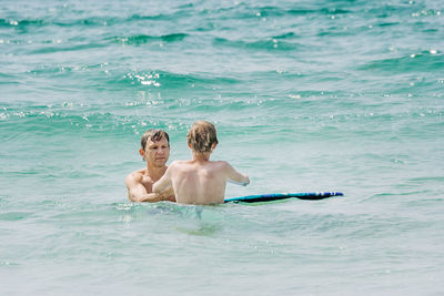 Rear view of shirtless boy swimming in sea