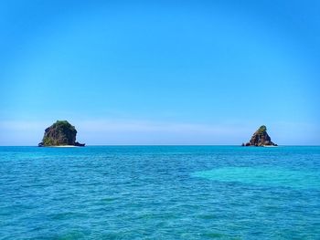 Rock formation in sea against blue sky