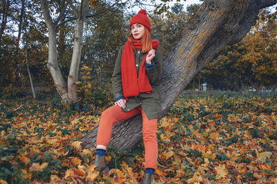 Autumn fashion portrait of stylish woman in bright orange knitted hat and scarf sitting 