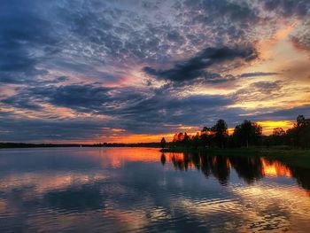 Scenic view of lake against dramatic sky during sunset