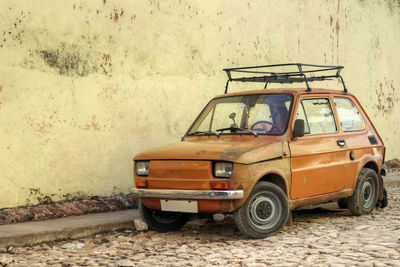 An old and small orange car on the streets of havana