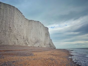 Rock formation on beach against sky