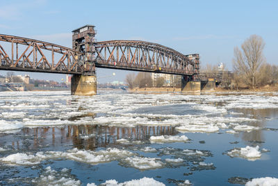 Bridge over river against sky during winter