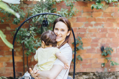 Happy mother and daughter against brick wall