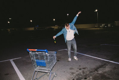 Full length of young man with arms raised at night