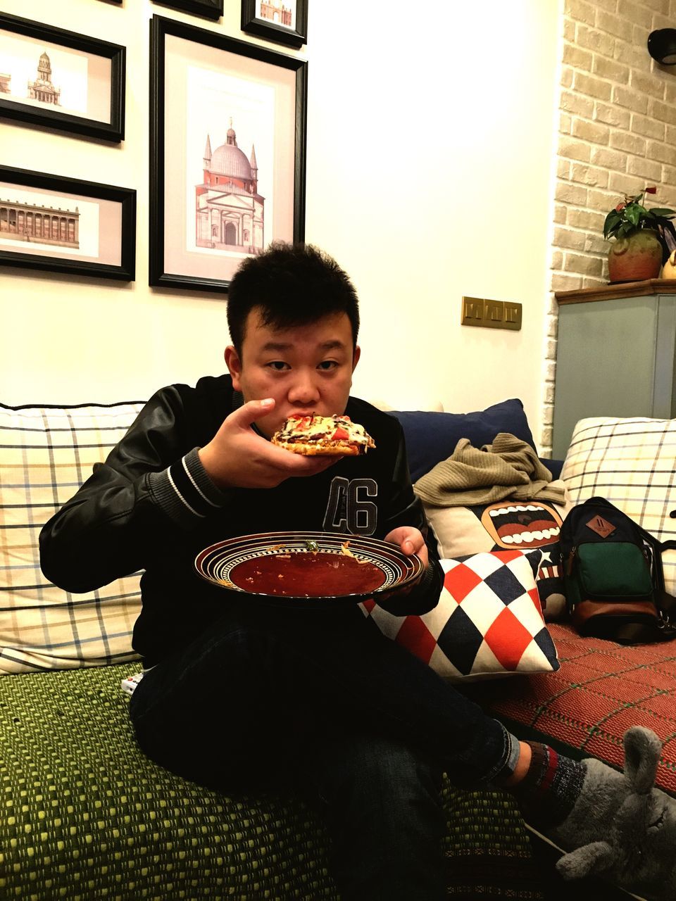 eating, front view, indoors, sitting, one person, real people, living room, men, only men, cheerful, food, people, one man only, young adult, adult, adults only, day