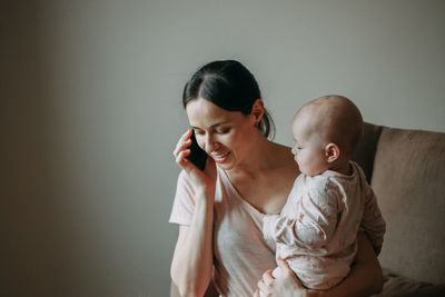 Mom holds her son in her arms and talks on a cell phone. selective focus, soft focus, defocused