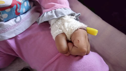 Midsection of child with adhesive bandage sitting in hospital