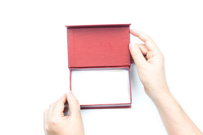 Close-up of hand holding book against white background