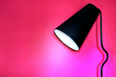 Close-up of illuminated floor lamp against pink background