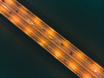 Low angle view of light trails over sea in city at night