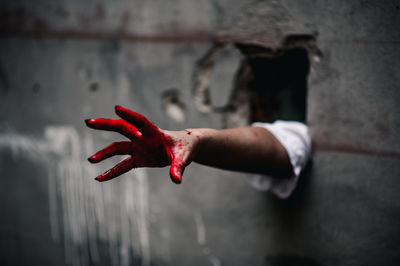 Close-up of hand against red wall