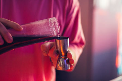 Midsection of bartender preparing drink in bar