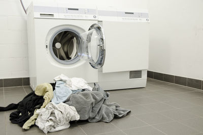 Heap of clothes by washing machine at home