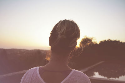 Rear view of woman standing by lake against clear sky